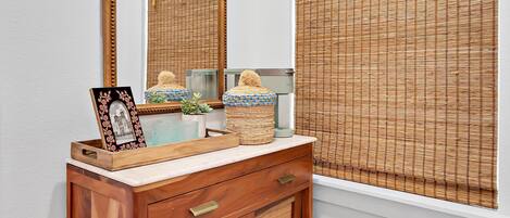 A wooden vanity with a mirror, a framed photo, and decorative items.