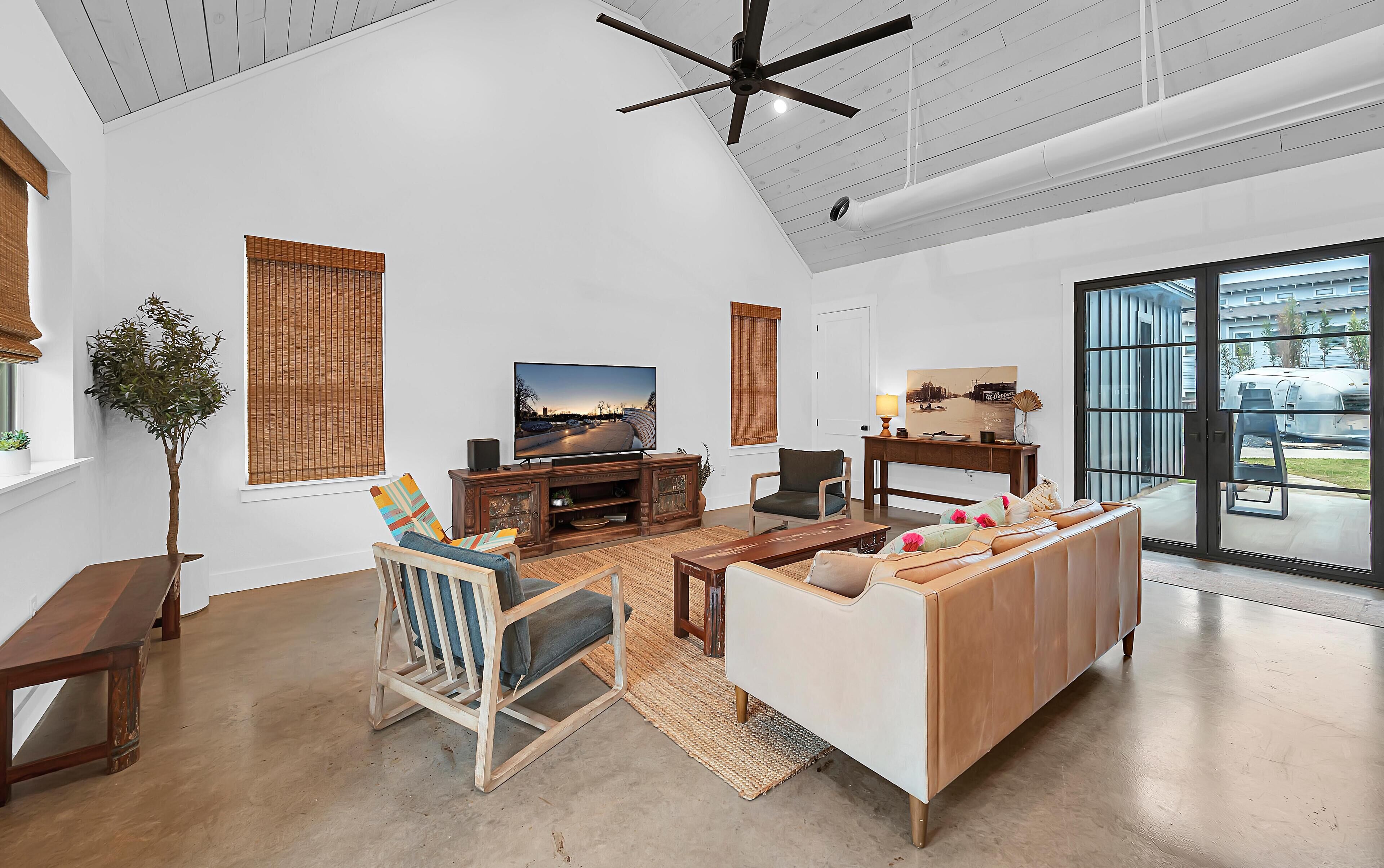 A spacious living room with a large TV, comfortable seating, and a ceiling fan.