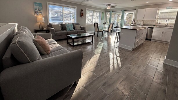 A modern living room with a grey sofa, a glass coffee table, and a dining area with chairs.