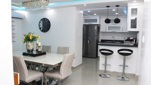 Una cocina moderna con armarios blancos, un refrigerador de acero inoxidable y una encimera negra.