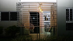 Un edificio moderno con baranda de metal, un sillón colgante y una mesa con sillas en su interior.