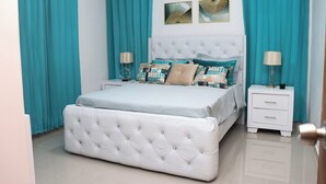 Un dormitorio ordenado con una cama grande, dos mesitas de noche y una mesilla.