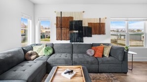A modern living room with a sectional sofa, a wooden coffee table, and a wall-mounted macrame piece.