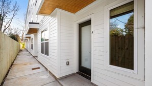 A row of white houses with wooden siding and a concrete pathway.