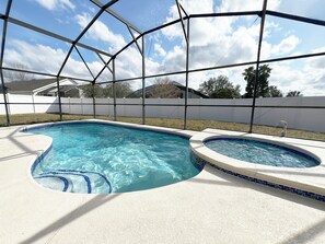 Piscina com área de água azul cristalina, cercada por grade branca e área coberta com estrutura de metal.