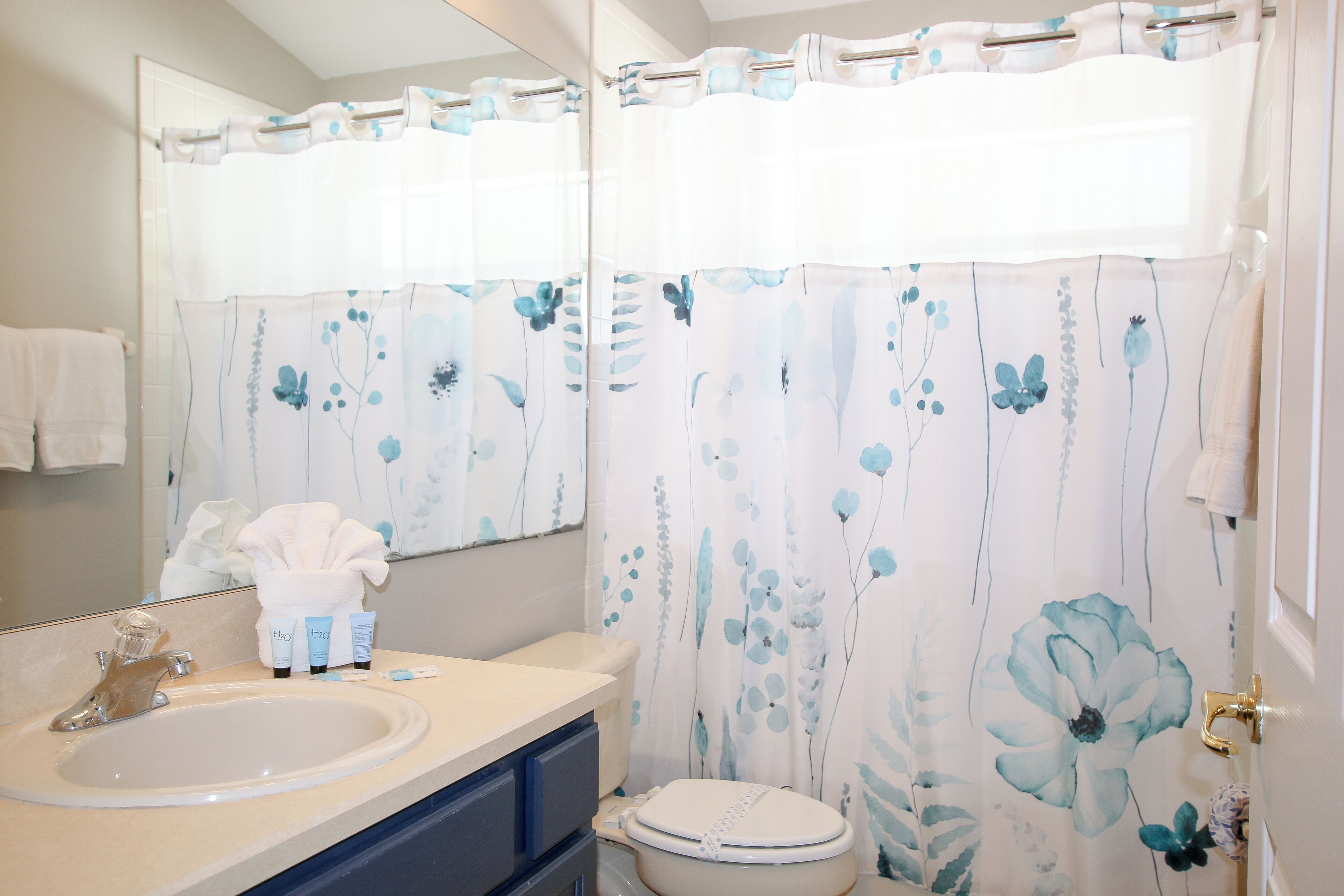 A bathroom with a sink, toilet, and shower curtain with floral patterns.