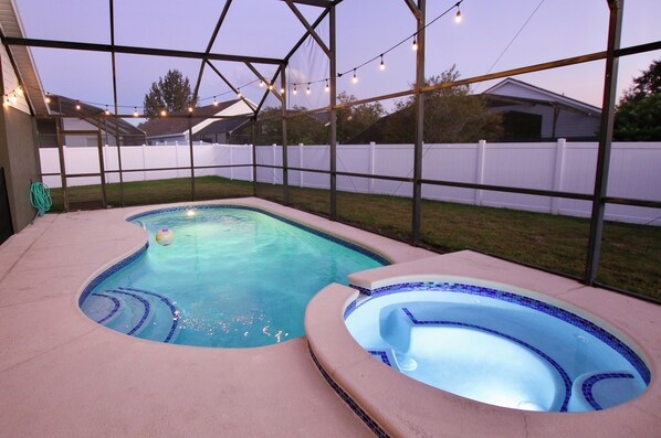 Um quintal com piscina e ofurô, rodeado por um espaço de varanda coberto.