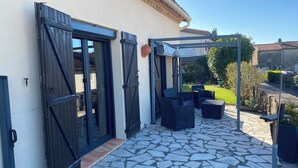 A patio with stone flooring, black shutters, and outdoor furniture. - HOUSE WITH A VIEW OF THE PYRENEES OF THE ARIEGE AT TREZIERS NEAR MIREPOIX (Tréziers)