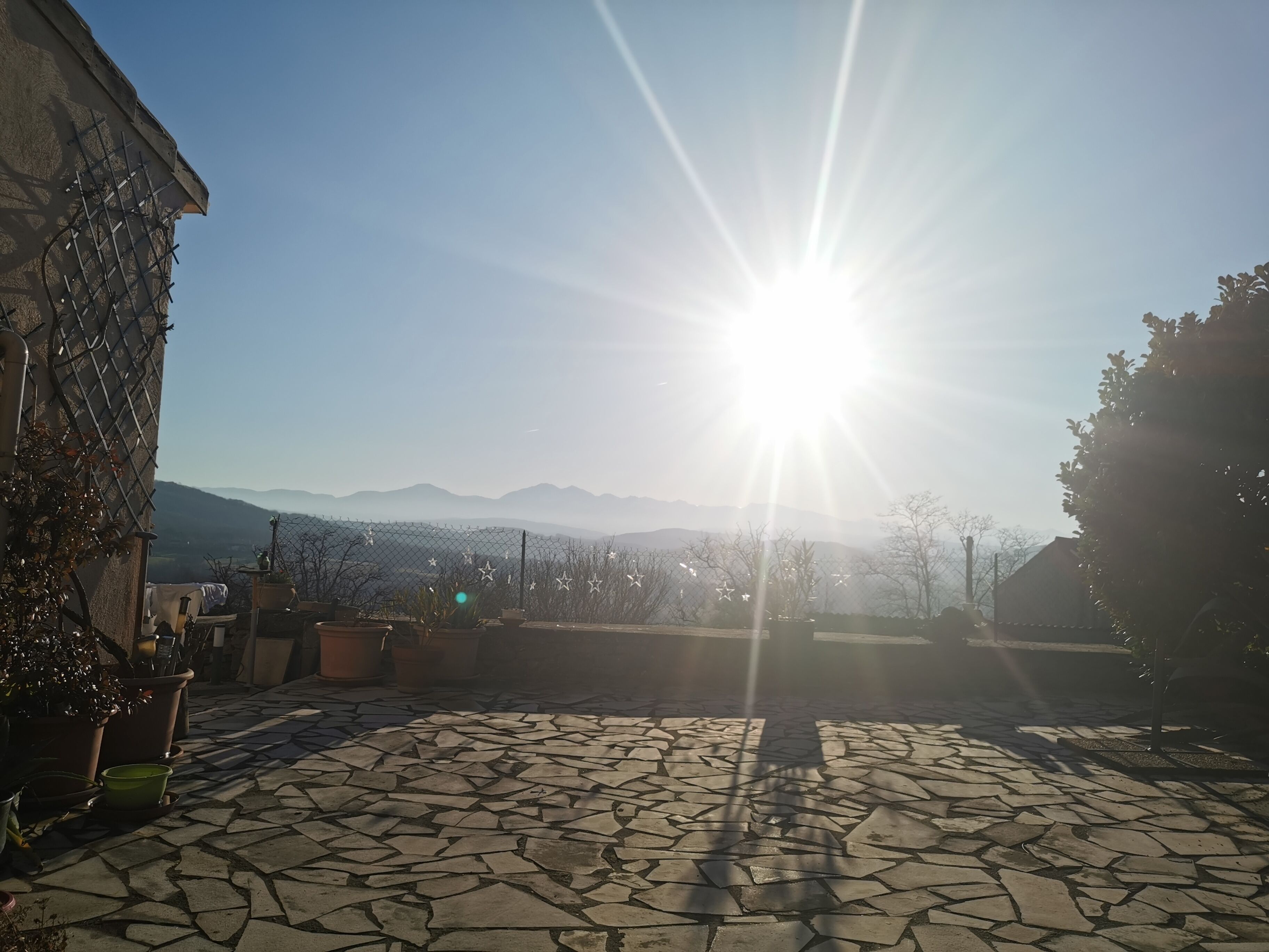 Un patio con piso de piedra, una cerca de metal y un edificio a un lado.
