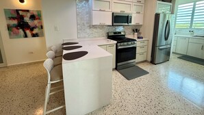 A modern kitchen with white cabinetry, a central island, a stainless steel refrigerator, and a microwave. - Located close to Isabel Segunda Vieques, downtown 4 bedrooms with pool. (Vieques)
