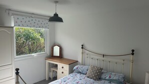 A bedroom with a bed, a dresser, a window, and a desk. - Cosy Holiday Park Chalet, Quiet Location, Child Friendly, Near Bude (Penstowe Holiday Park, Kilkhampton)