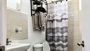 A bathroom with a toilet, sink, and shower curtain. - Playa del Carmen Apartment (Playa del Carmen)