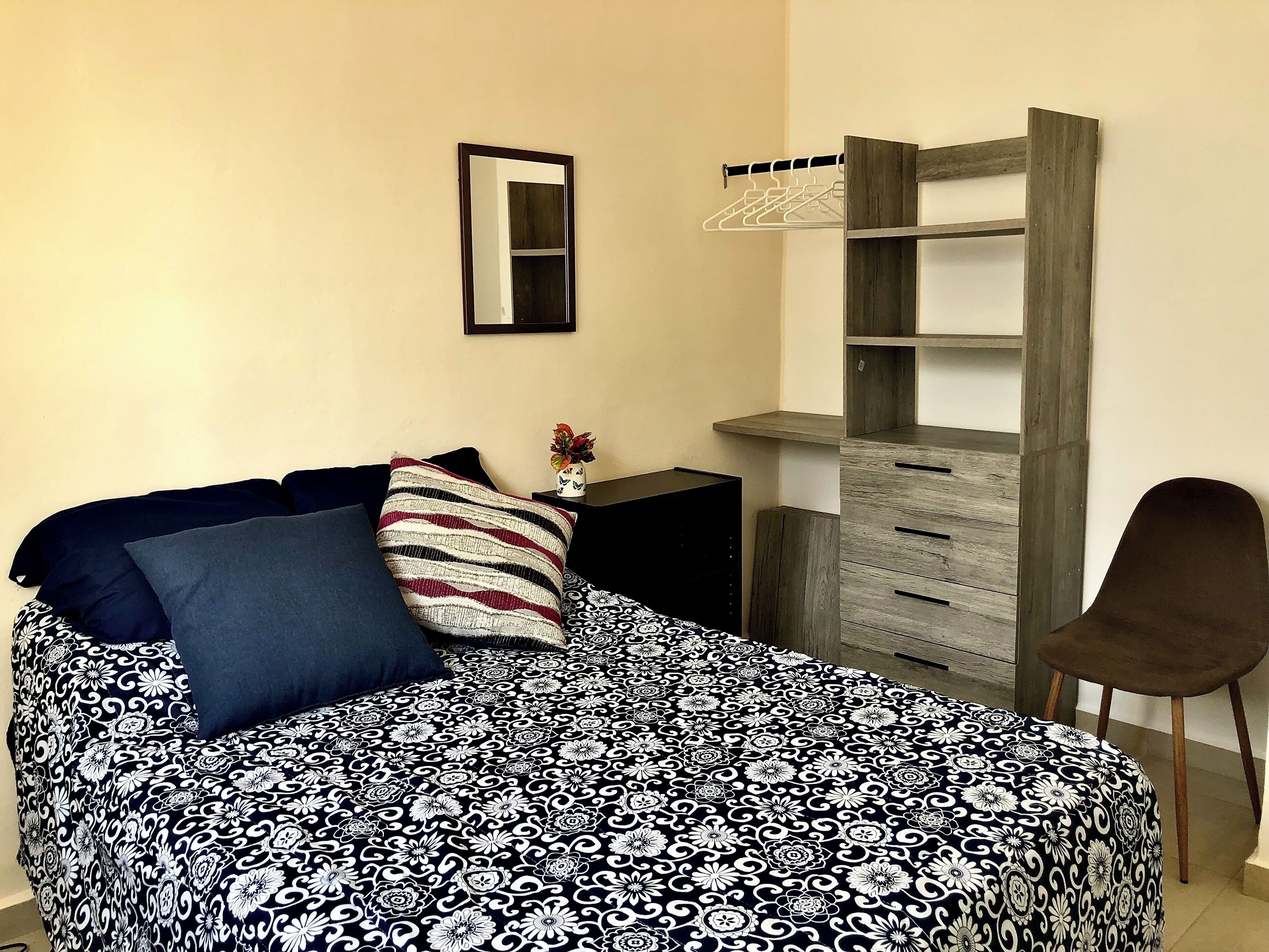 Ein Schlafzimmer mit Bett, Nachttisch, Kommode und einem Sessel.