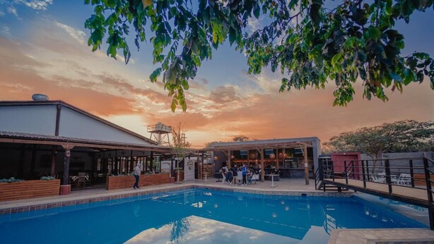 A swimming pool with a covered area, a water tower, and a bar/lounge area with people. - Hotel Fundo San Rafael  (Nazca)