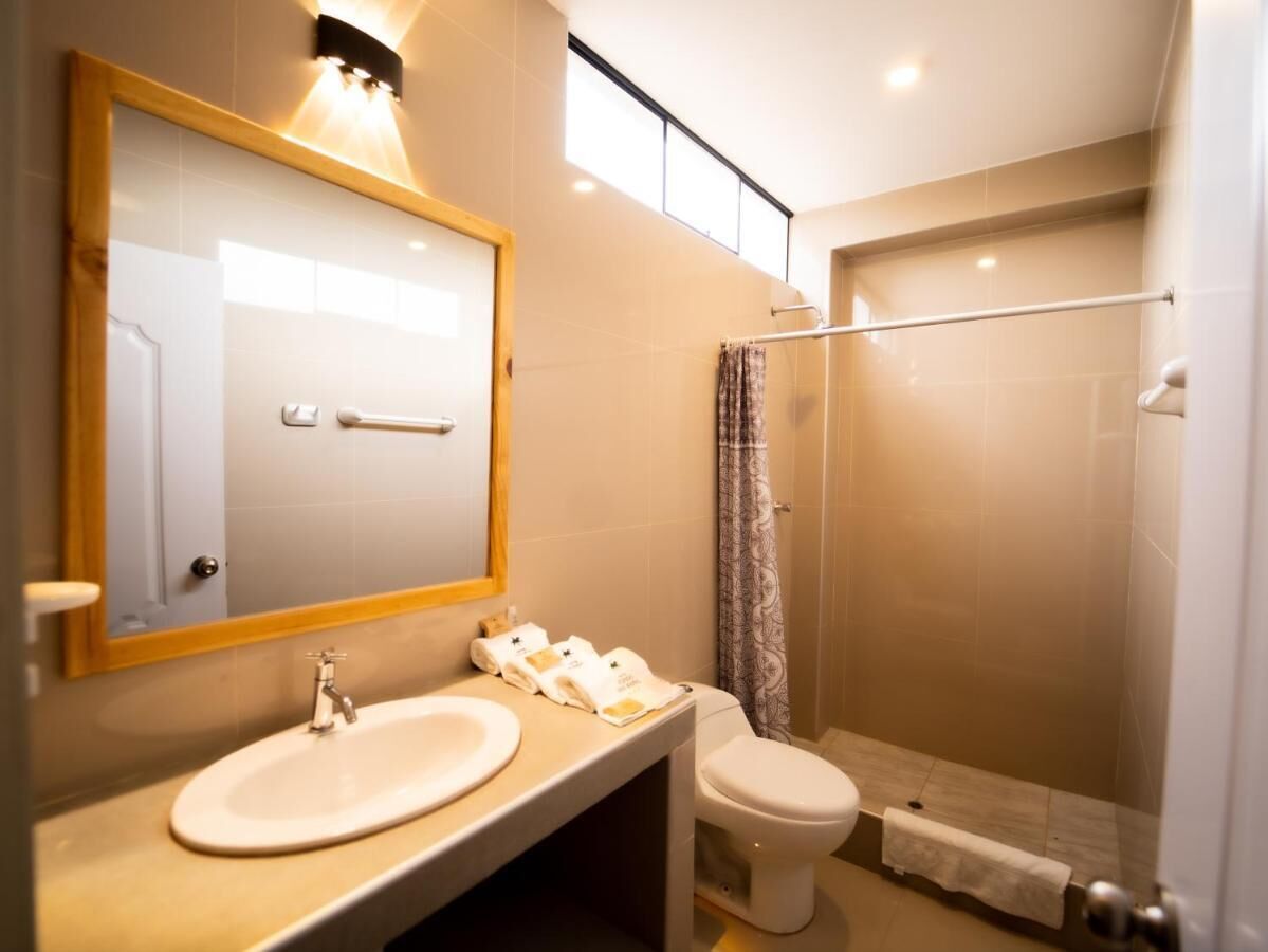 Een moderne badkamer met een grote spiegel, twee wasbakken, een toilet en een douchecabine met glazen wanden.