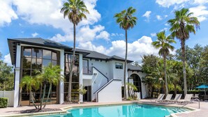 Una moderna casa con piscina, palme e un cielo azzurro limpido.