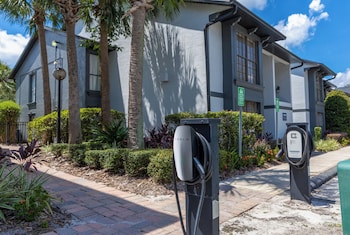 A compact, white, front-loading washing machine in a small laundry room with a door on one side. at The Fold Hotels Orlando