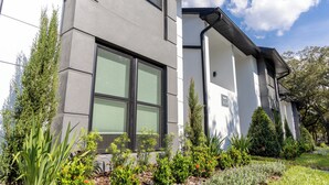 Un edificio moderno con ampie vetrate e un giardino curato, ricco di piante e fiori.