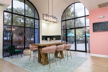 A gym with exercise equipment, a bench, and a view of a swimming pool through large windows. at The Fold Hotels Orlando