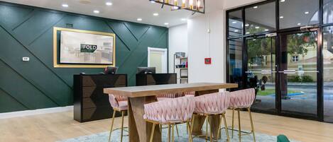 A modern hotel lobby with a large wooden reception desk, green walls, and a patterned rug.