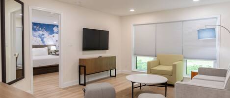 A modern living room with a bed, a TV, a sofa, and a coffee table.