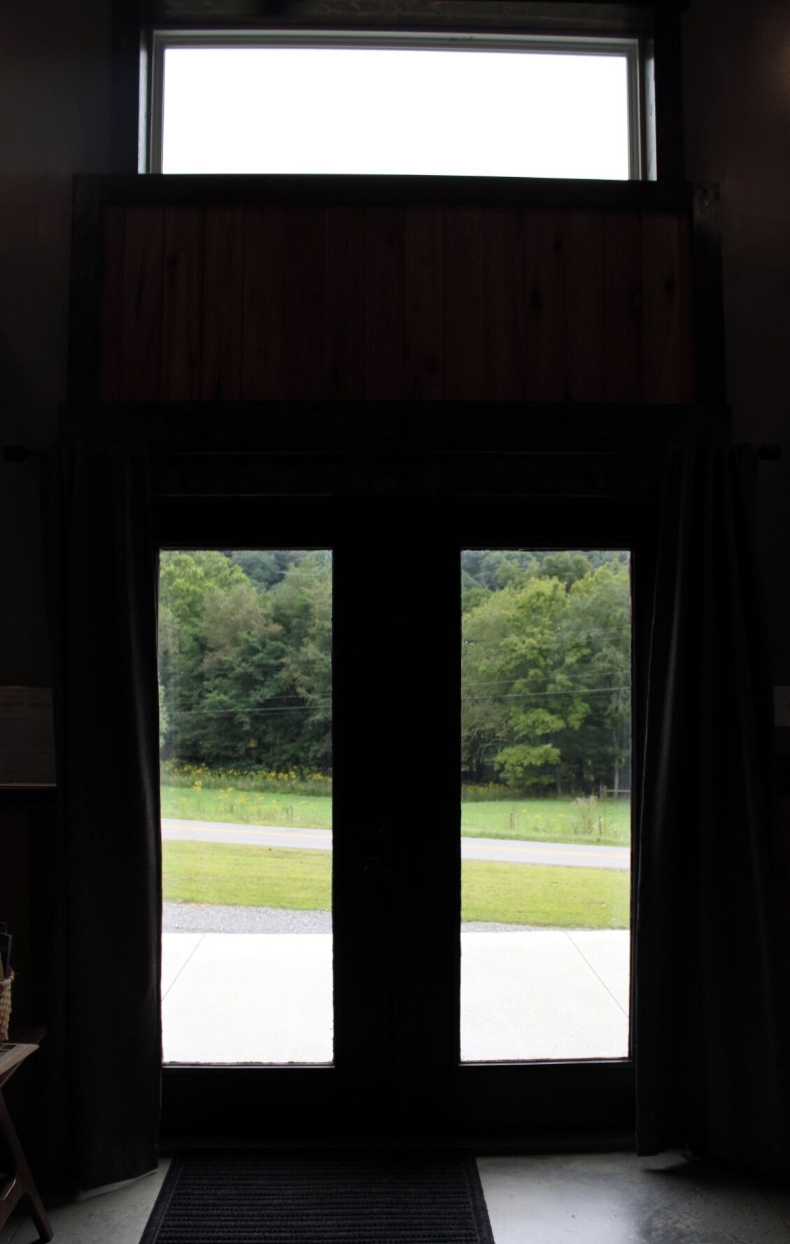 A doorway with a view of a road and greenery outside.