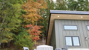Un bâtiment moderne doté d’un toit en pente, de grandes fenêtres et d’un patio aménagé avec des sièges extérieurs.