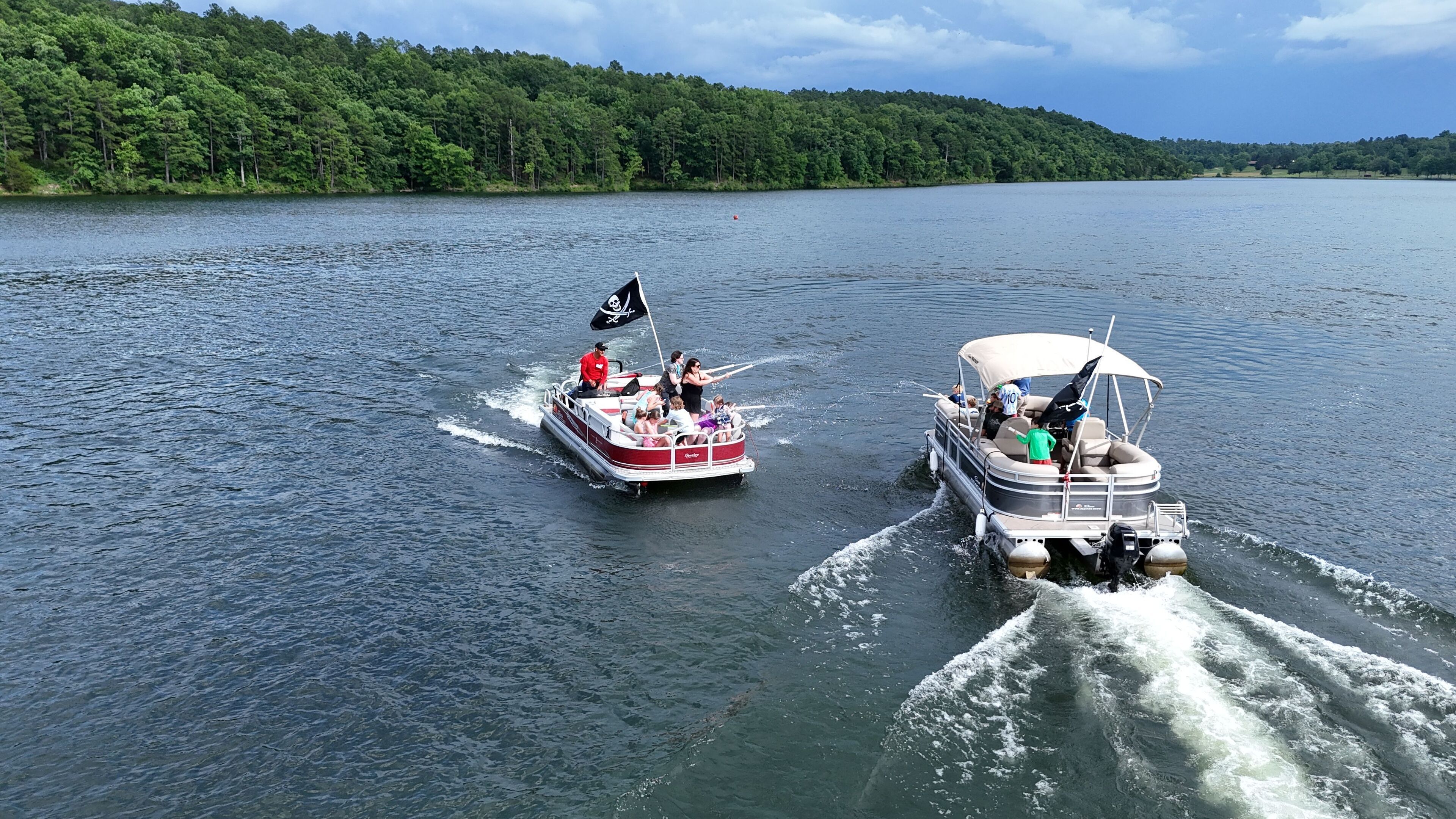 Two boats on a lake with a forested shoreline.