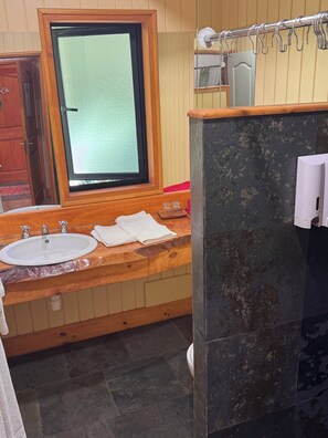 Une salle de bain avec un meuble-lavabo en bois, deux vasques, un miroir et un porte-serviettes.