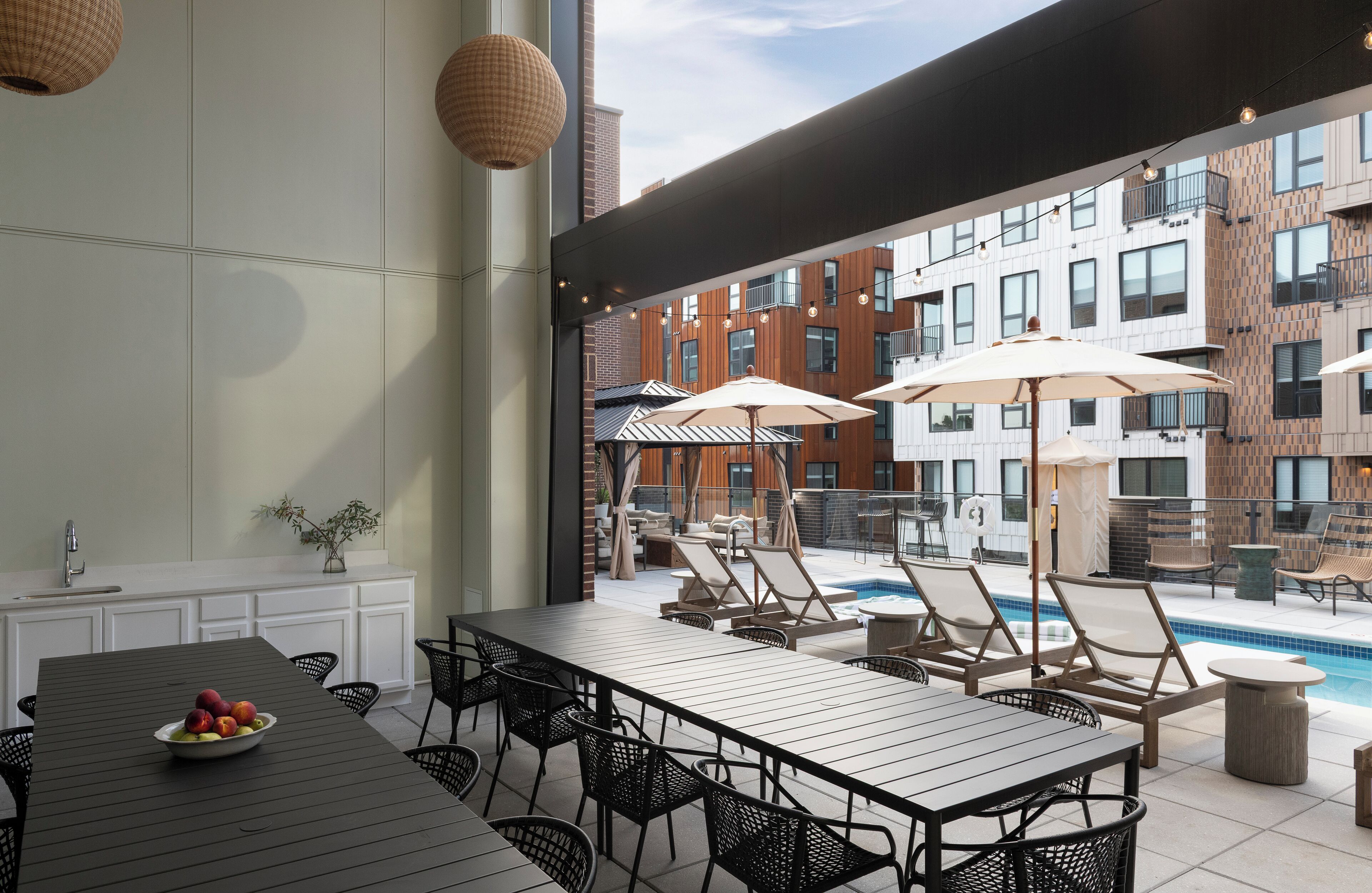 An outdoor dining area with a pool, lounge chairs, and umbrellas.