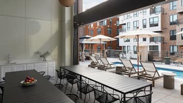 An outdoor dining area with a pool, lounge chairs, and umbrellas.