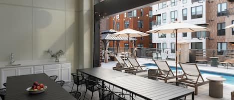 An outdoor dining area with a pool, lounge chairs, and umbrellas.