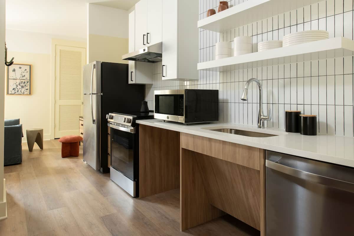 A modern kitchen with stainless steel appliances, wooden cabinets, and a tiled backsplash.