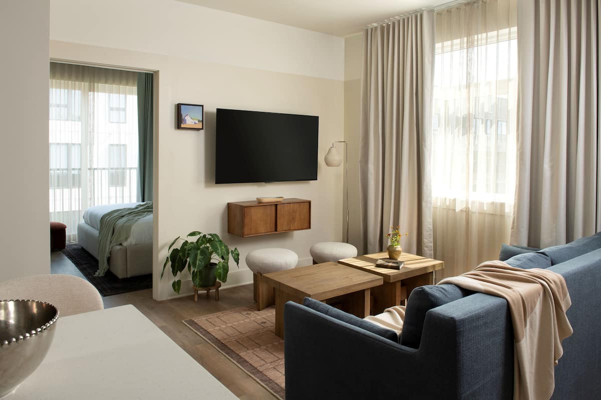 A modern living room with a flat-screen TV, a wooden coffee table, a sofa, and a dining table.