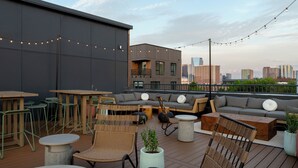 A rooftop terrace with outdoor seating, including a sofa, chairs, and tables. - Mint House Nashville Marathon Village by Kasa (Nashville)