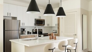 A modern kitchen with a central island, stainless steel appliances, and black pendant lighting. - Mint House Nashville Marathon Village by Kasa (Nashville)