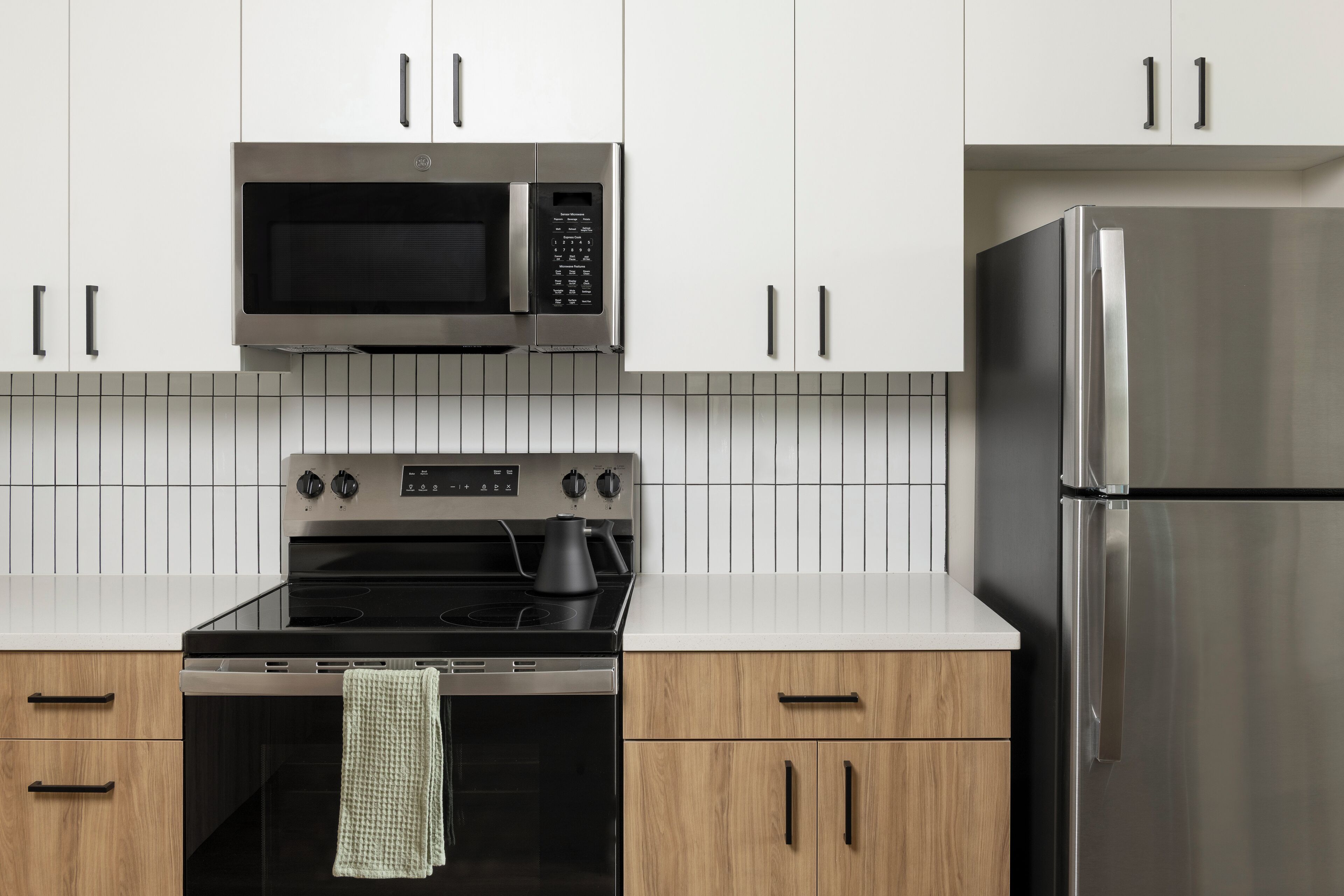 A modern kitchen with stainless steel appliances, including a microwave, oven, and refrigerator.