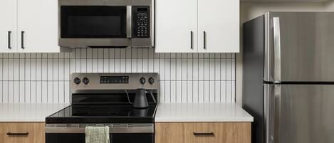 Una cocina moderna con electrodomésticos de acero inoxidable, incluyendo un microondas, horno y refrigerador.
