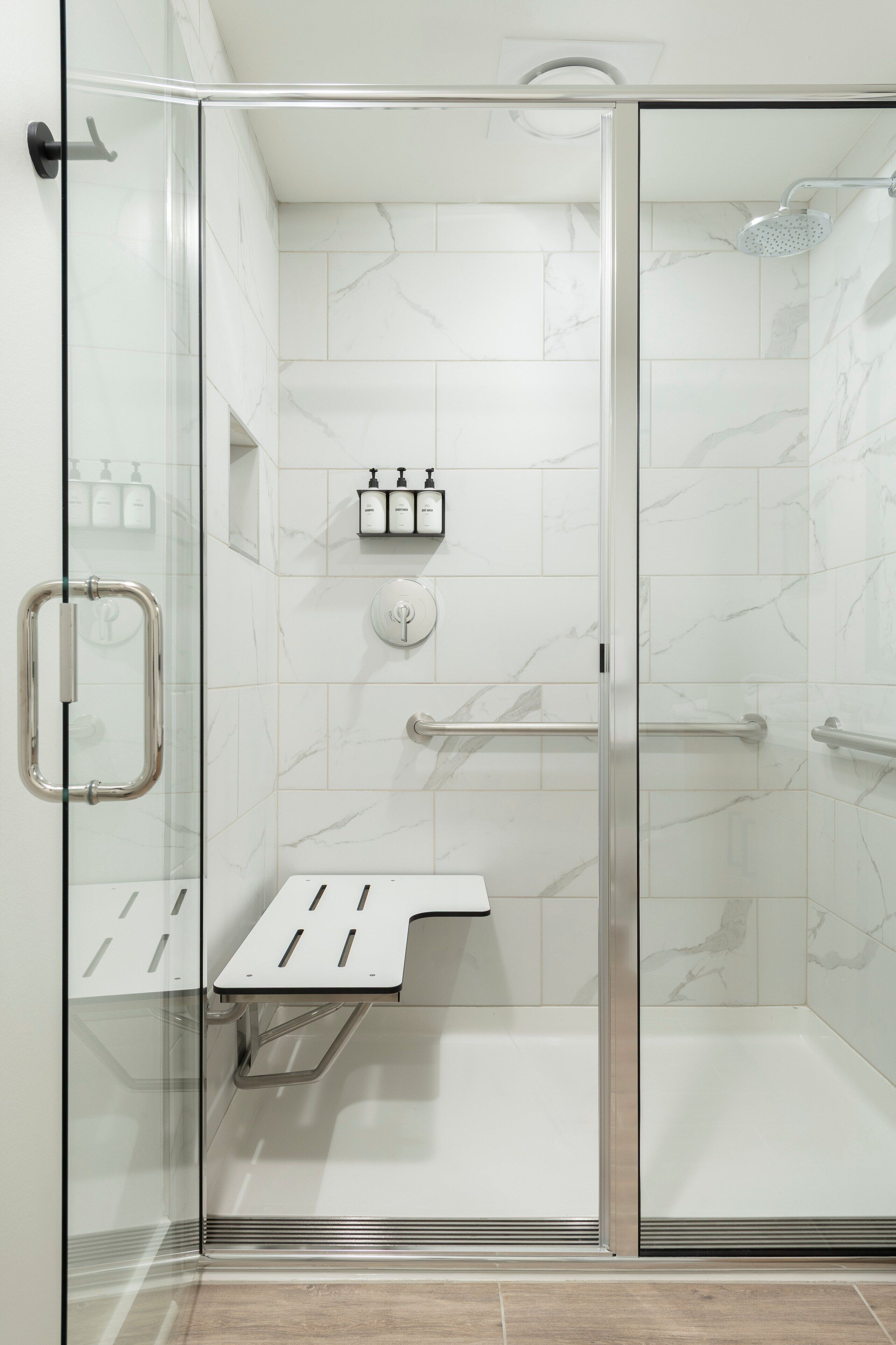 Un espace douche moderne doté d’une porte en verre, d’un pommeau de douche à main et d’un panneau de commande.
