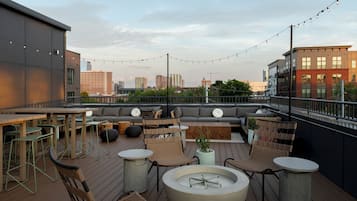 Una terraza en la azotea con asientos al aire libre, una chimenea y vistas panorámicas del horizonte urbano.