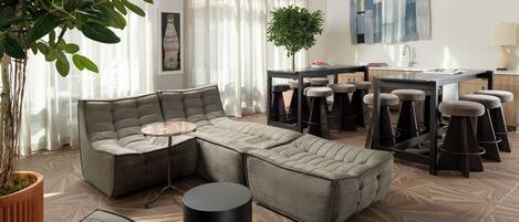 A modern living room with a sectional sofa, a round coffee table, and a dining area with bar stools.