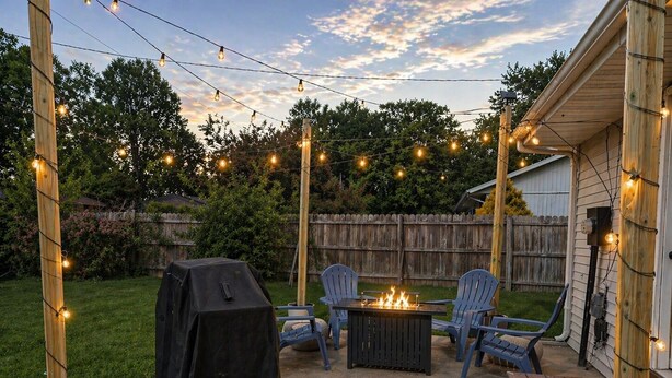 A backyard patio with a grill, chairs, and a fire pit.