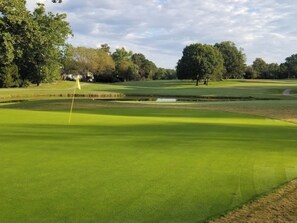 A golf course with a putting green, sand bunkers, and a pond. - Lex Holmes Luxury House (Fort Washington)