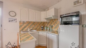 A compact kitchen with white cabinets, a tiled backsplash, a dishwasher, and an oven.