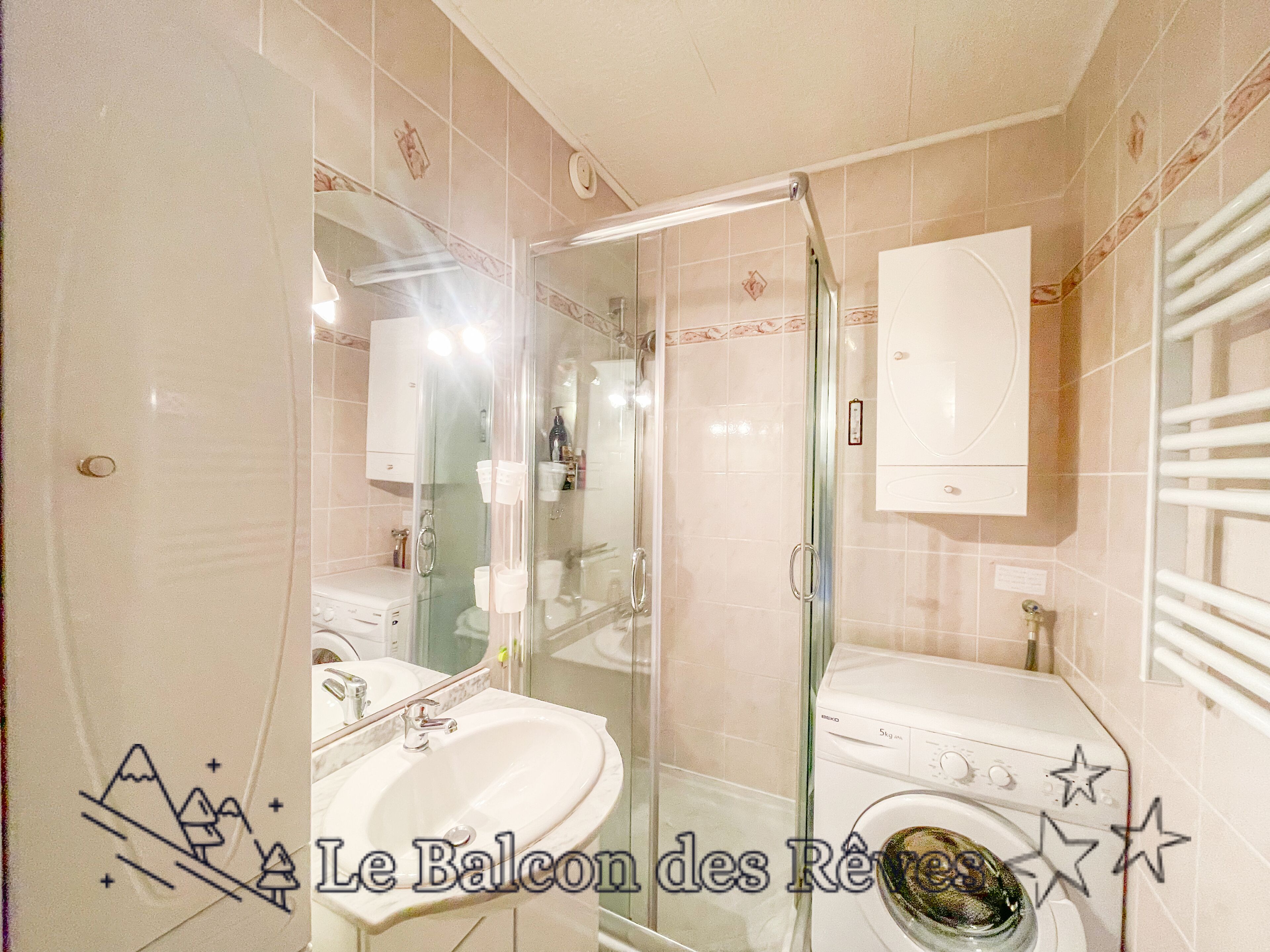A bathroom with a glass-enclosed shower, a sink, a toilet, and a washing machine.