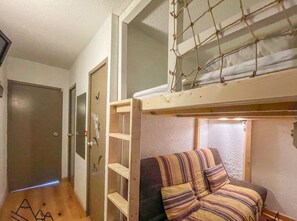Een kamer met een stapelbed, een deur en een klein raam.