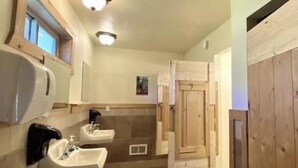 A bathroom with two sinks, a window, and wooden doors. - West Yellowstone Station At Mountain River Ranch (Ririe)