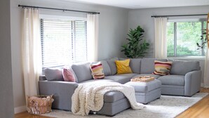 A modern living room with a grey sectional sofa, a white knitted throw, and a small side table.