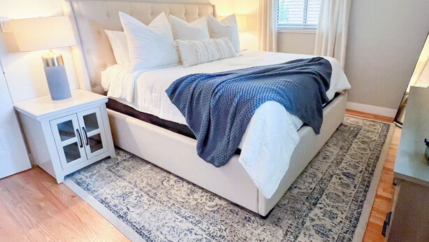 A bedroom with a bed, nightstand, and a window with curtains.