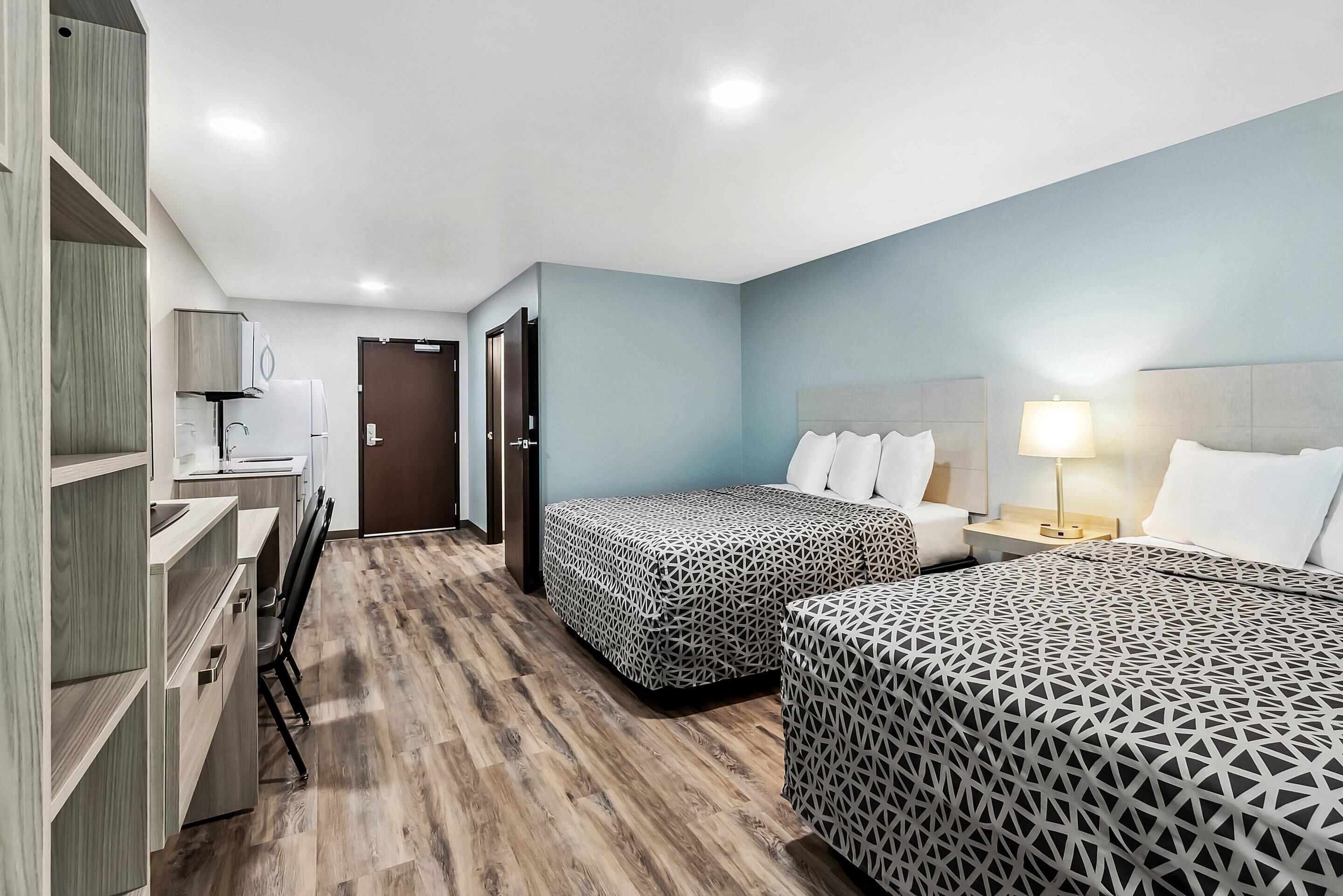 Habitación de hotel con dos camas, un escritorio y un armario.